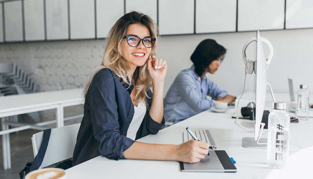 Beautiful female office worker carrying out administrative work for company. Indoor portrait of cute blonde student doing homework with asian universuty friend..