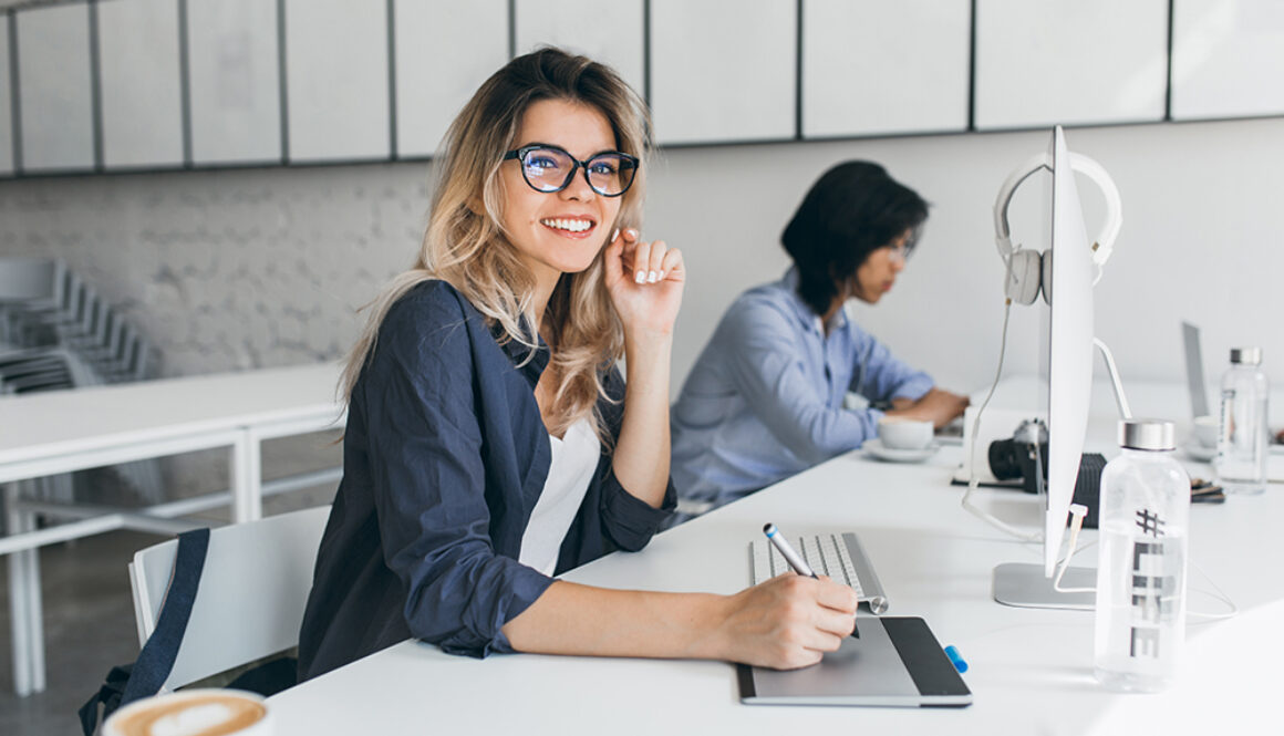 Beautiful female office worker carrying out administrative work for company. Indoor portrait of cute blonde student doing homework with asian universuty friend..